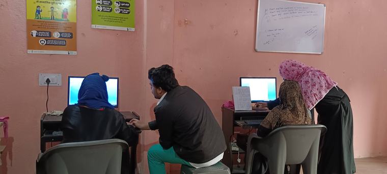 A facilitator guiding learners at the computers